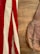 A vintage leather bag lies on a wooden surface, next to a fabric with red and white stripes.