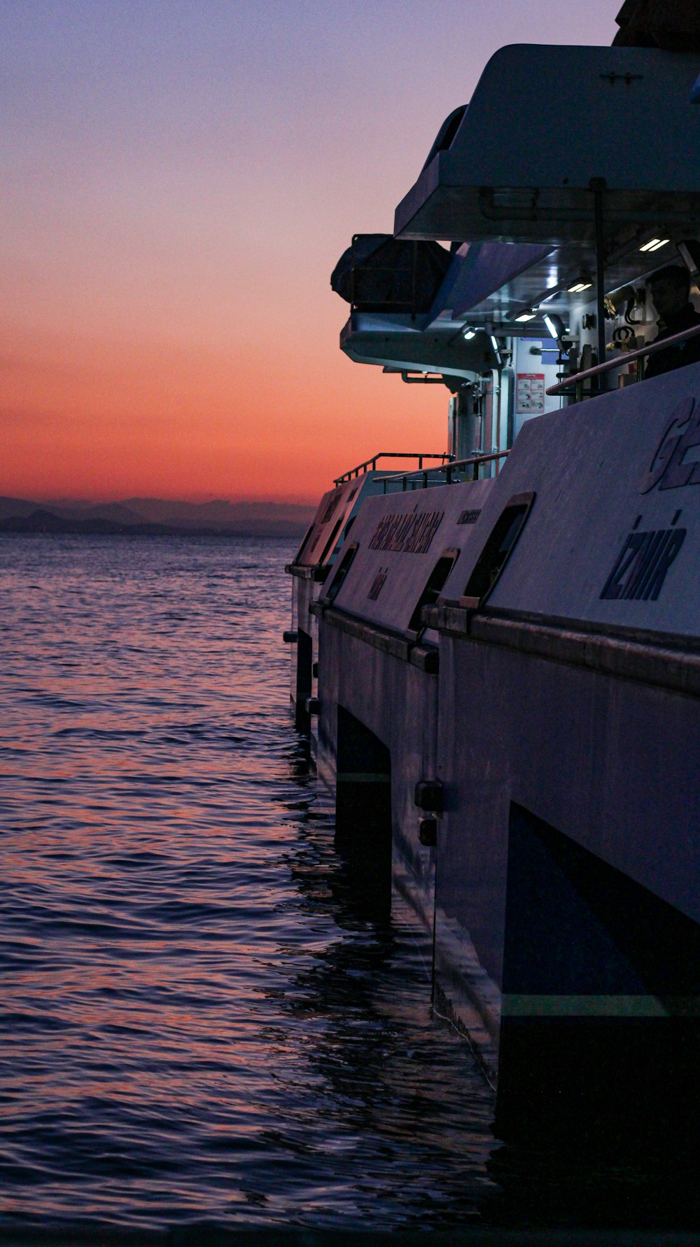 a boat sitting in the water at sunset