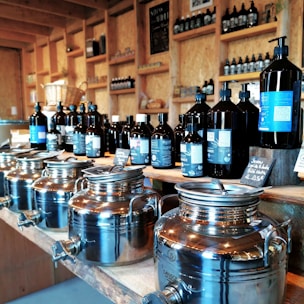 Bottles of ayurvedic pain relief oil and enzyme syrups displayed on a wooden shelf.
