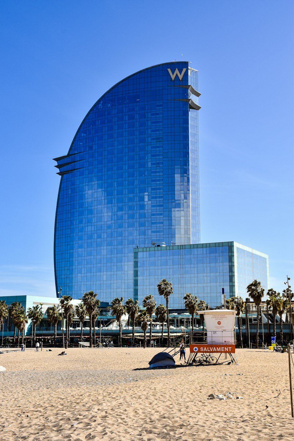 un grand bâtiment bleu assis au sommet d’une plage de sable