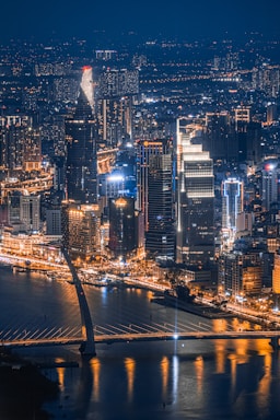 a night view of a city with a bridge in the foreground