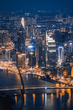 a night view of a city with a bridge in the foreground