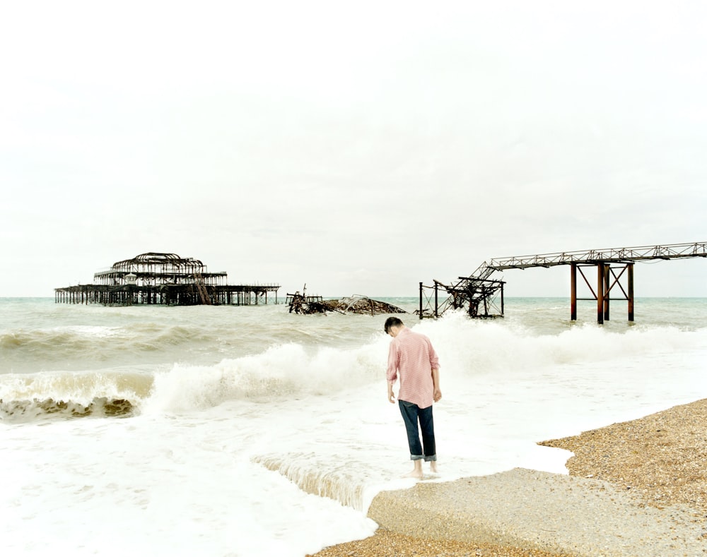 a man standing on a beach next to the ocean