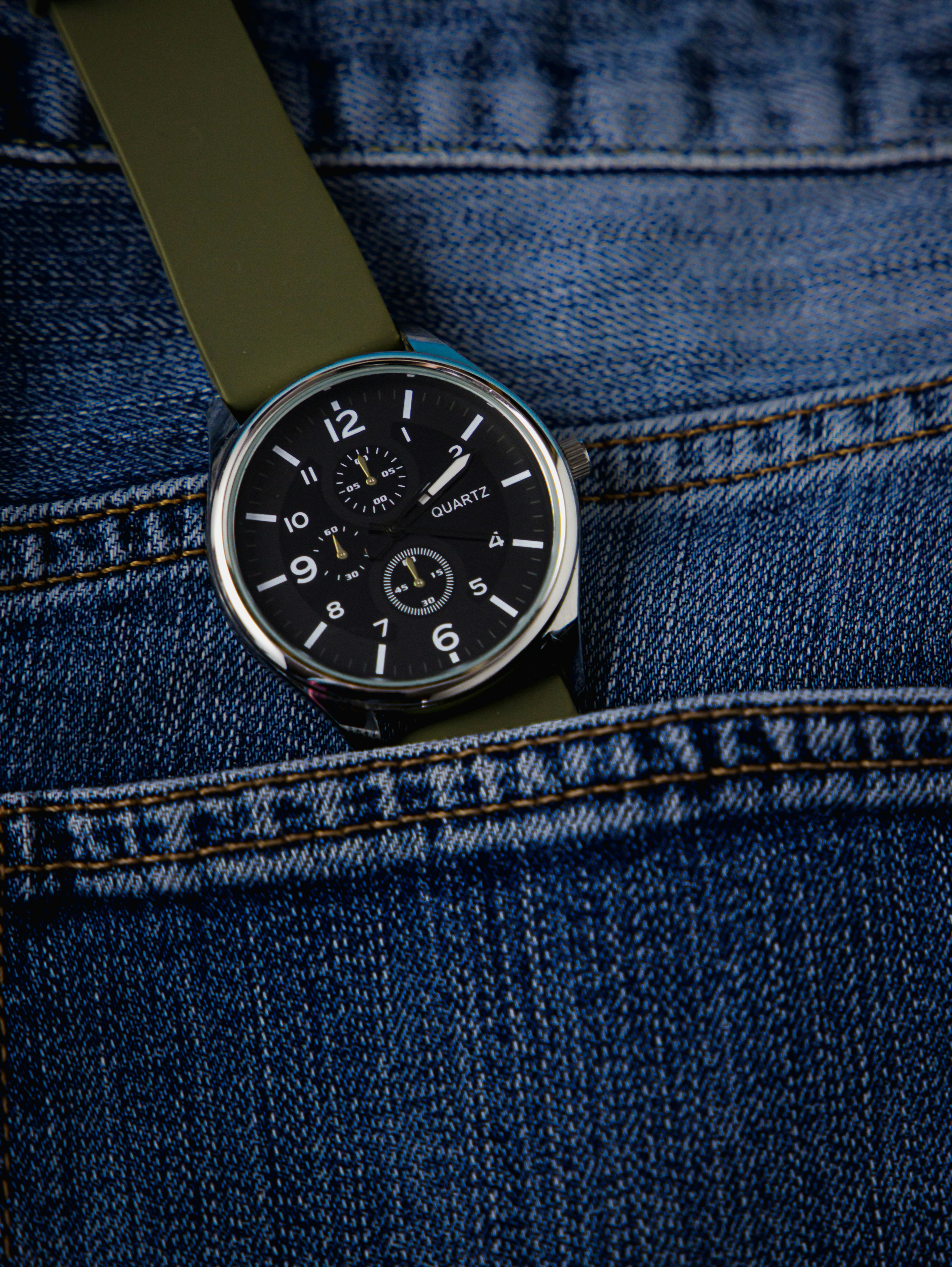 Nahaufnahme einer Uhr in der Tasche einer Jeans