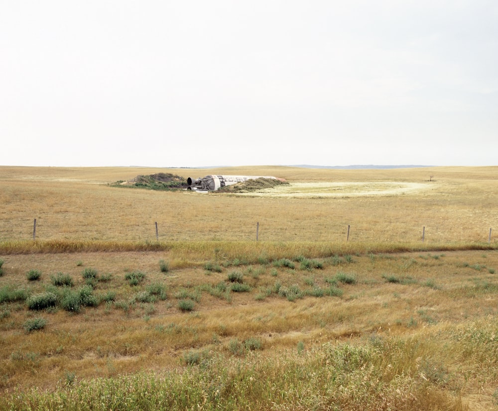 a large open field with a crashed rocket in the middle of it