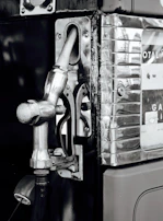 Side view of a vintage gas pump restored to highlight riveted steel plates and chrome accents.