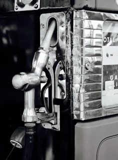 Side view of a vintage gas pump restored to highlight riveted steel plates and chrome accents.