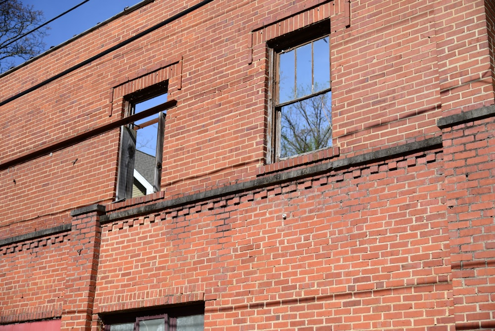 a red brick building with two windows and a street sign