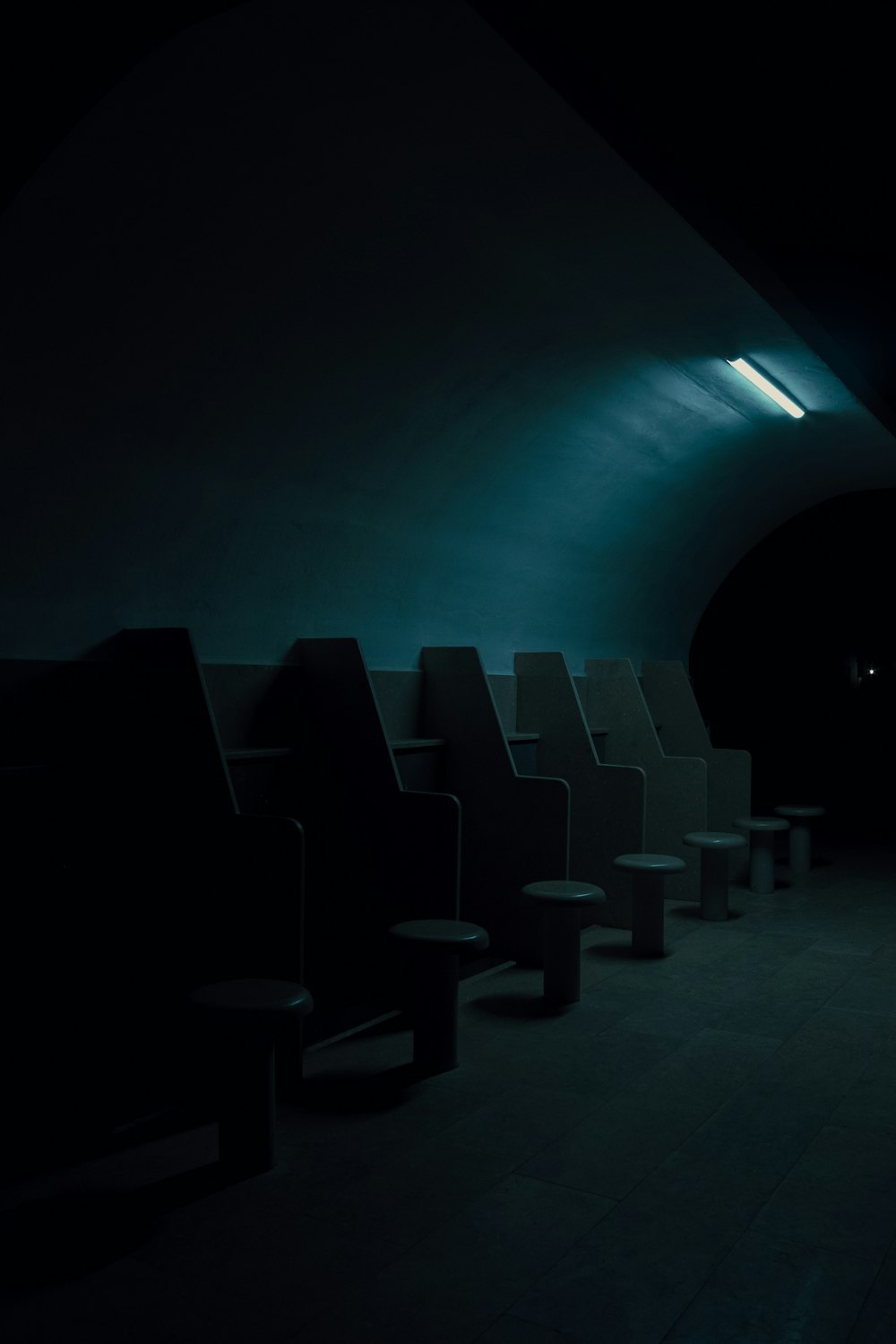 a dimly lit room with chairs and stools