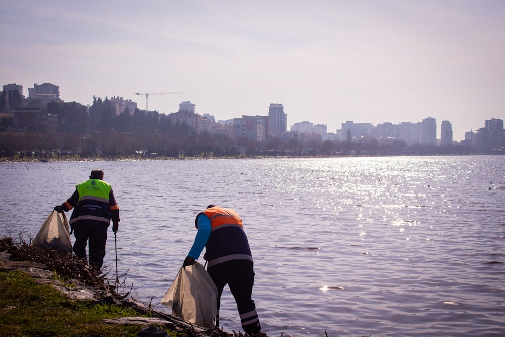 a couple of men standing next to a body of water