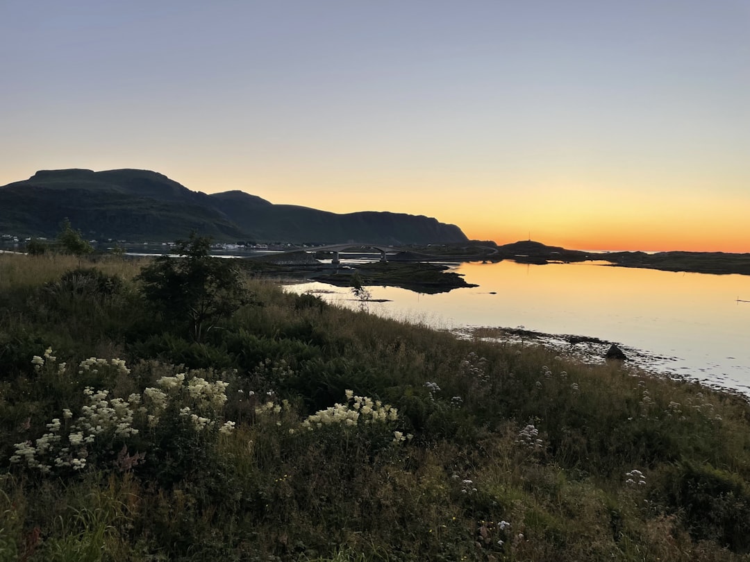 The sun is setting over a body of water, sunset with mountain in background