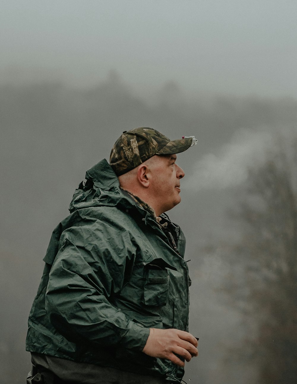 a man in a green jacket standing in the fog