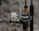 Several fishing reels are attached to rods, showing a variety of rods and reels close together. The focus is on the intricate details of the reels, which appear to be wet, suggesting they have been used recently or are in a humid environment.