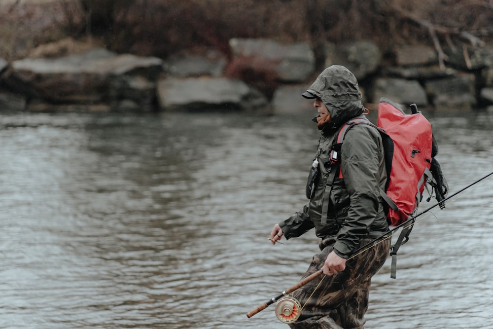 a man with a red backpack and a fishing pole