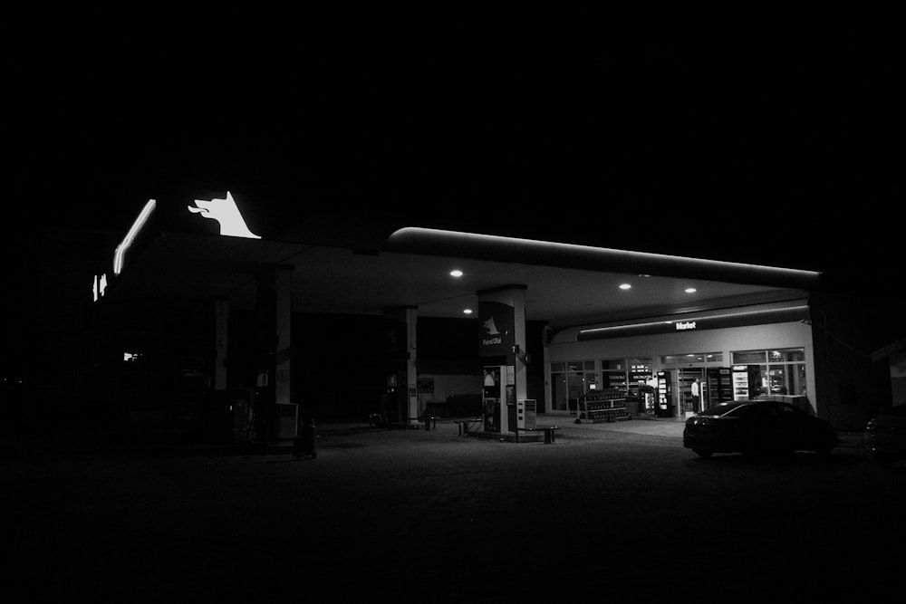 a black and white photo of a gas station at night