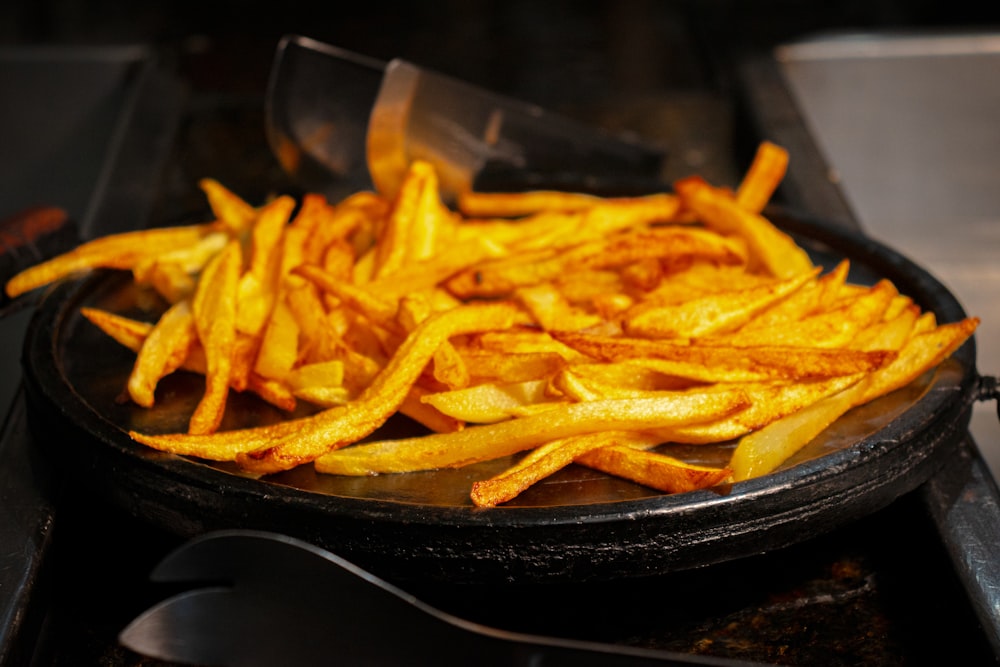 a frying pan filled with french fries on top of a stove