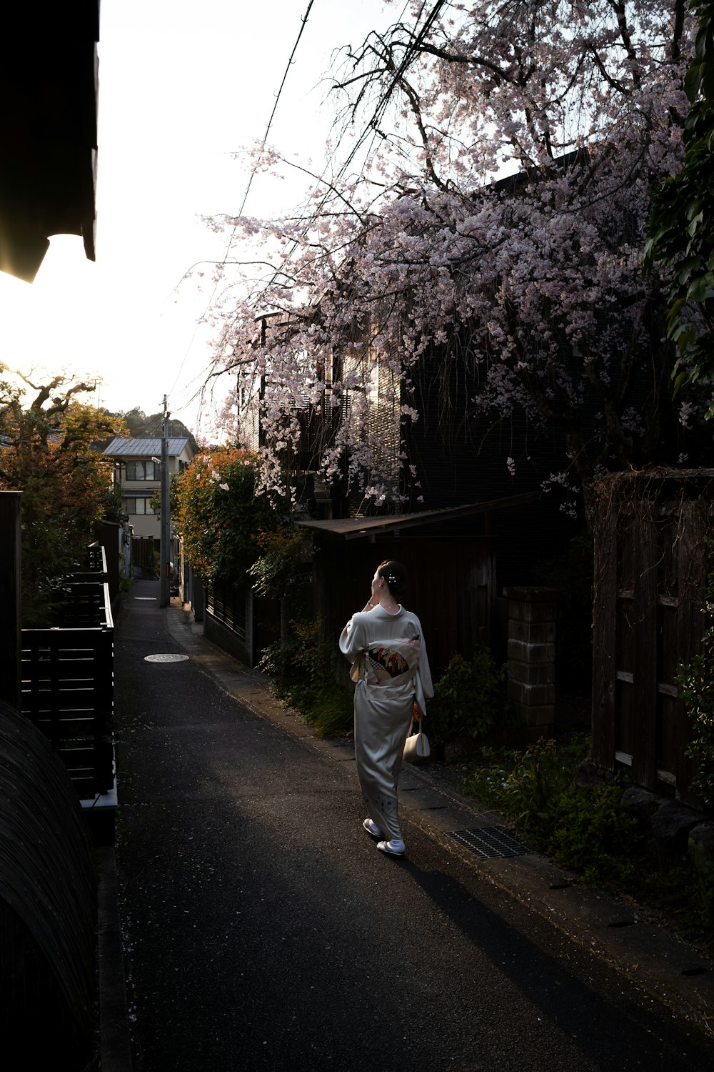 a woman walking down a street next to a tree