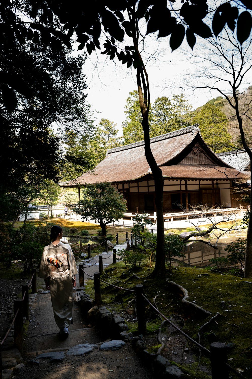 a woman in a kimono walking down a path