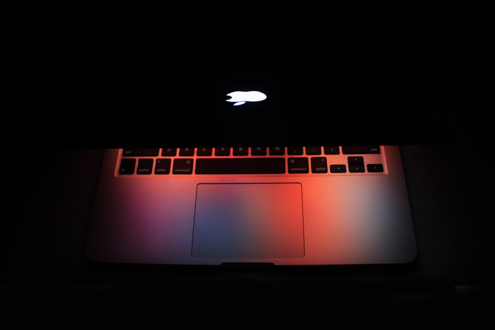 an apple laptop lit up in the dark