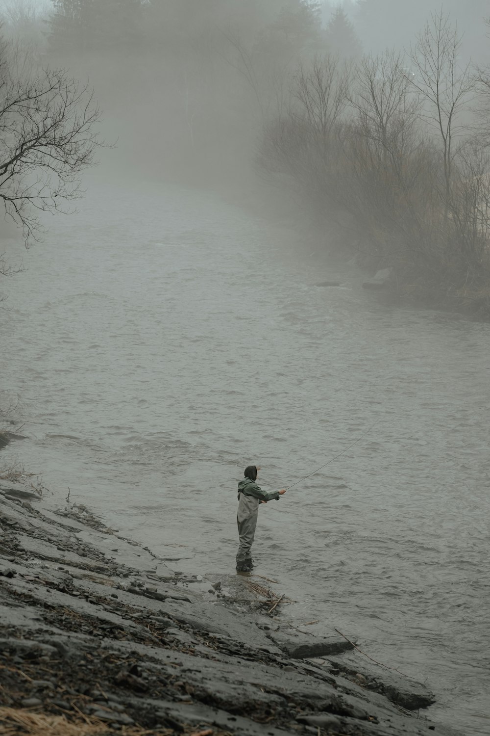 a man standing in a river holding a fish