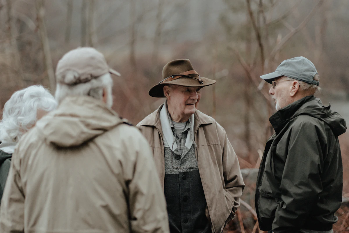 Three older club mates in fishing gear chatting by the river