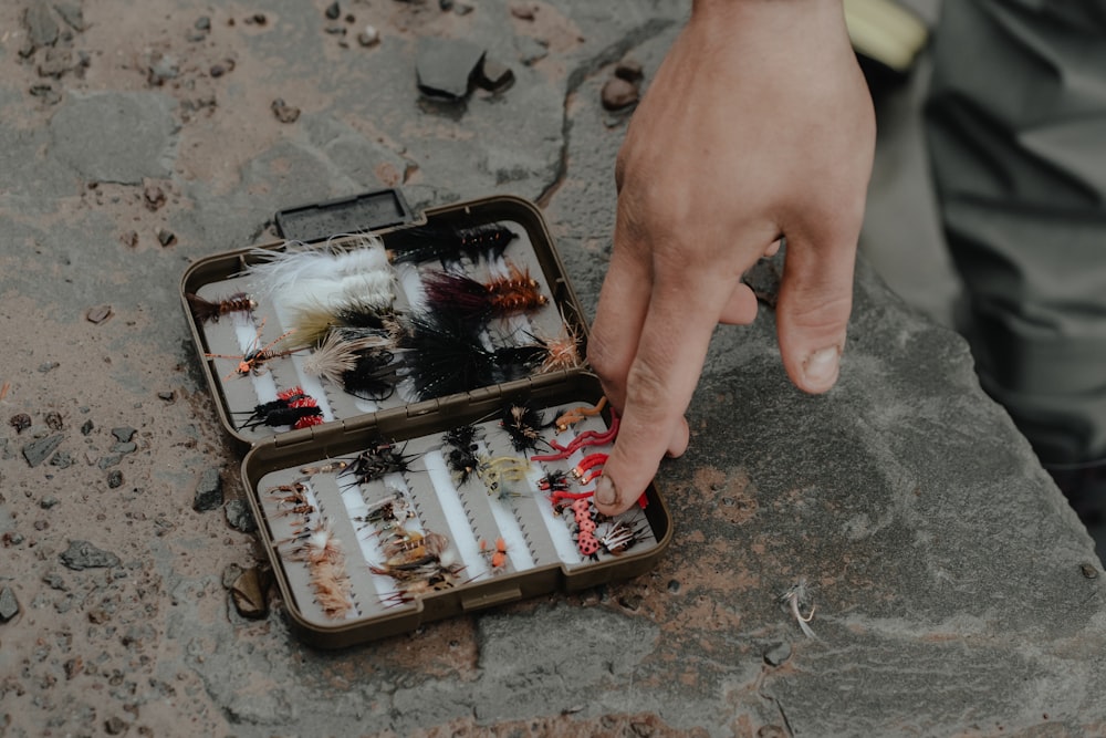 a man is holding a case of fishing lures