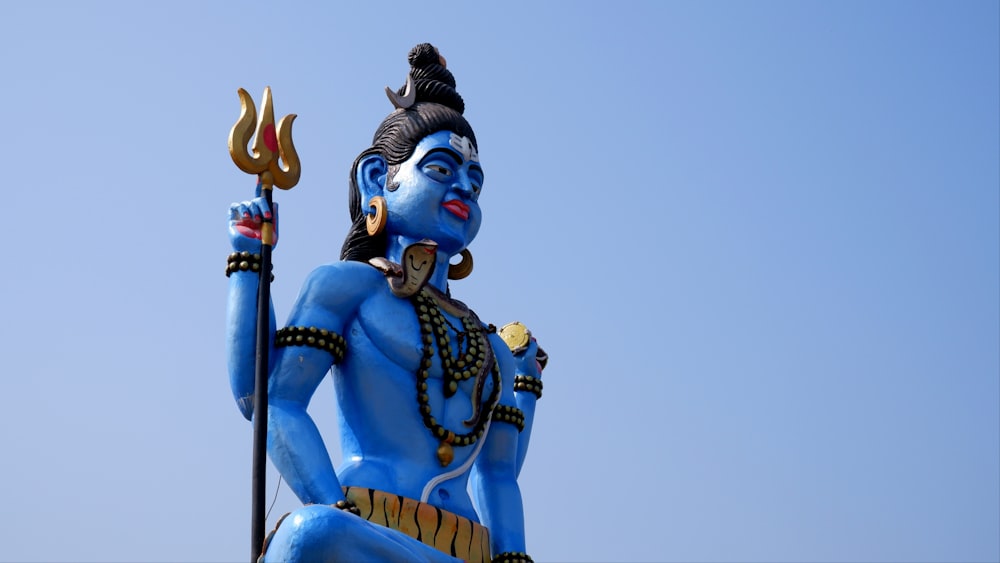 a statue of a hindu god holding a staff