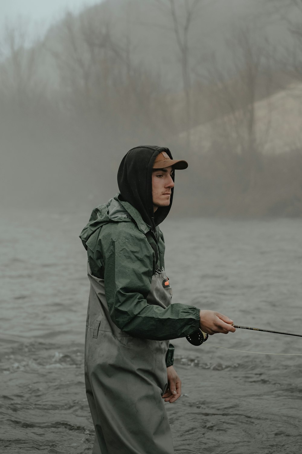 Un homme debout dans l’eau tenant une canne à pêche