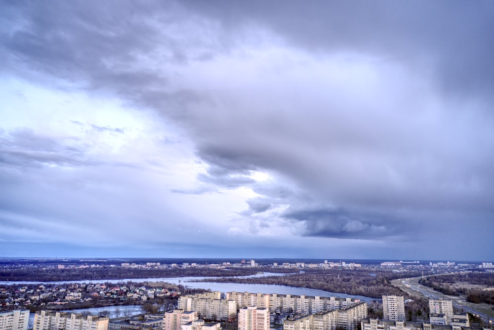 a cloudy sky over a city with a river in the foreground