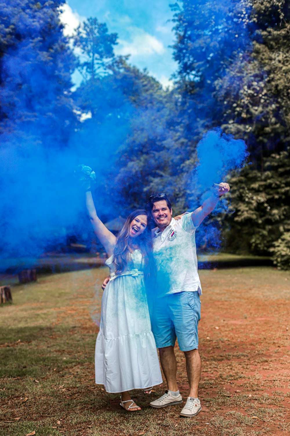 a man and a woman holding blue smoke bombs