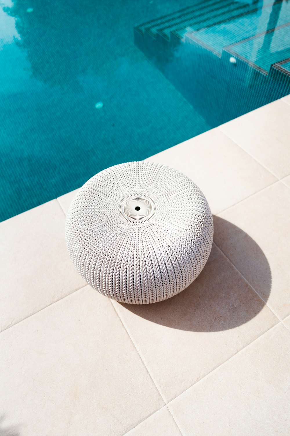 a white round object sitting on the ground next to a swimming pool