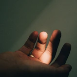 An elegant close-up of hands holding a glowing, translucent human design chart against a dark background.