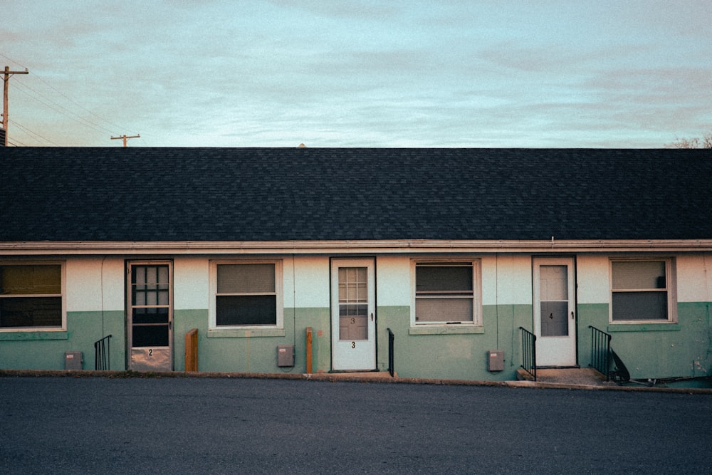 a motel building with a black roof and a parking lot