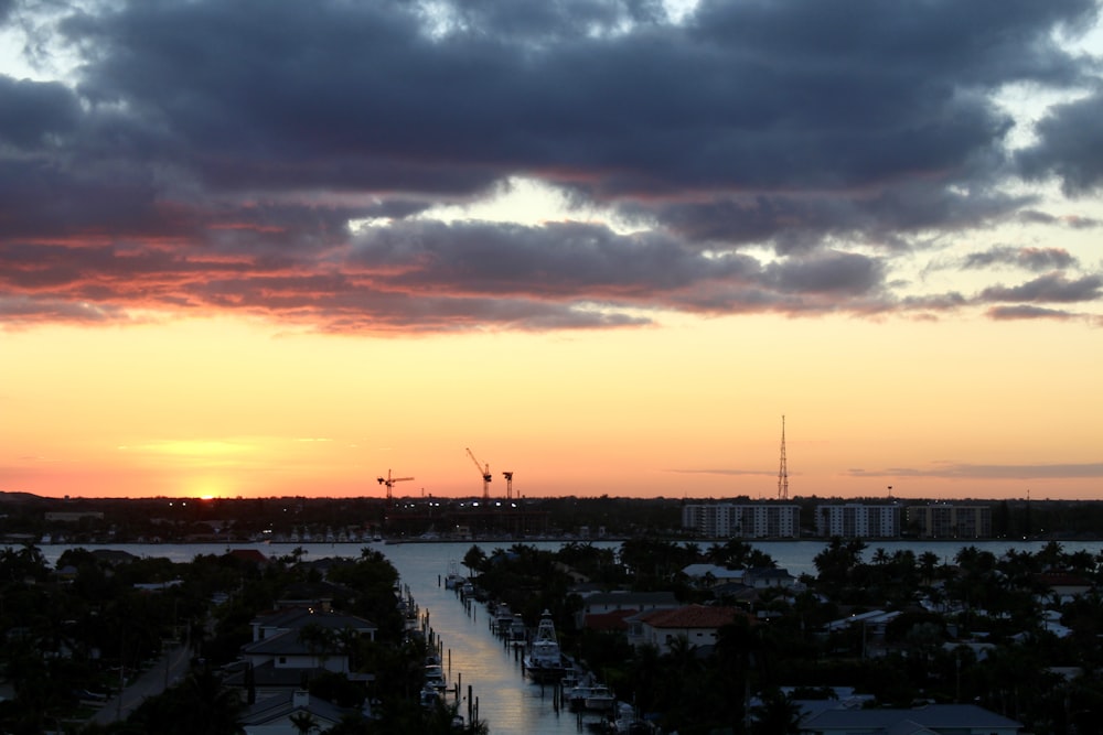 the sun is setting over a city and a body of water