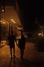 two people walking down a sidewalk holding hands