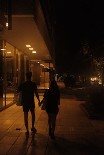 two people walking down a sidewalk holding hands