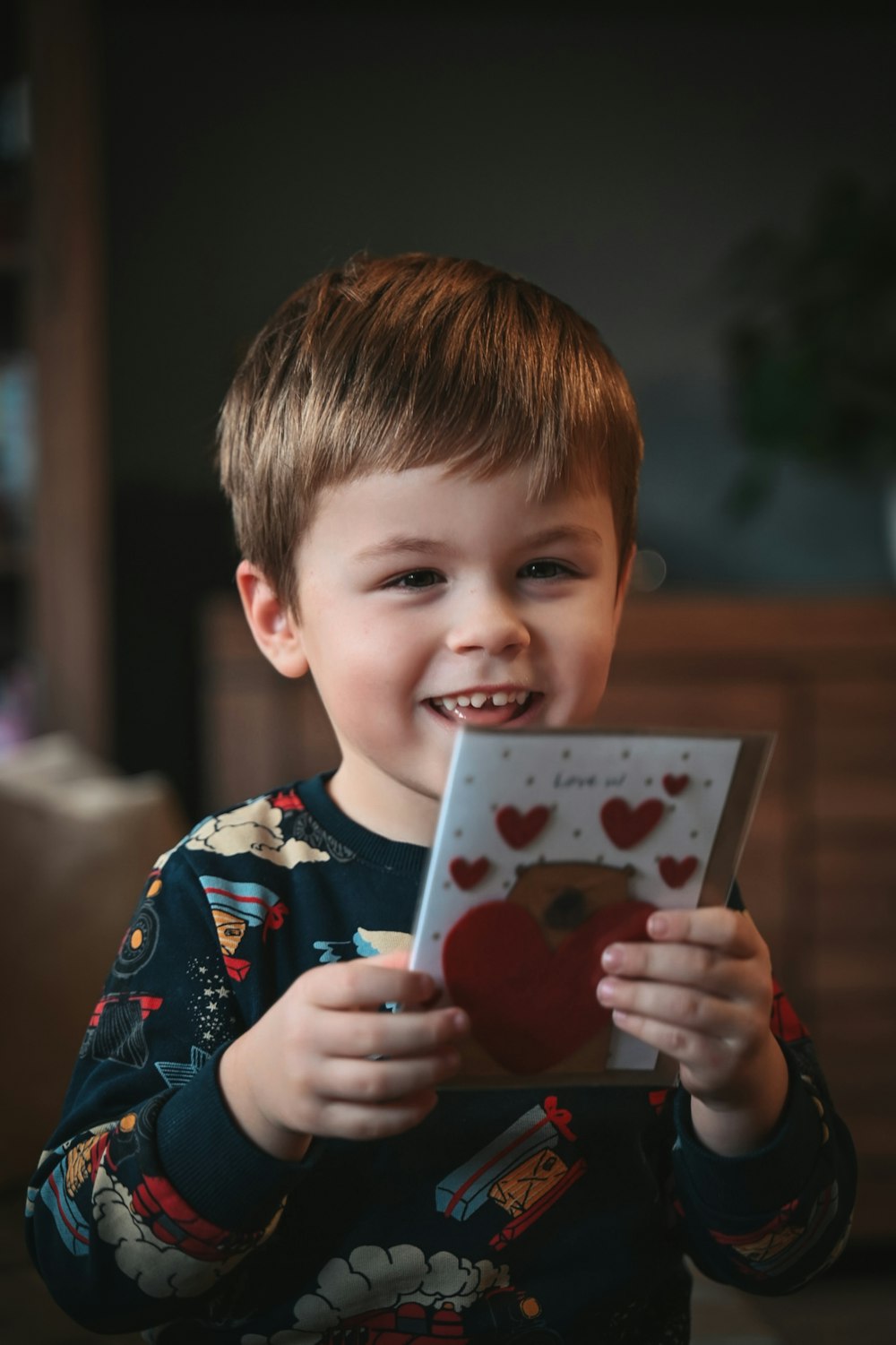 a young boy holding a card with hearts on it