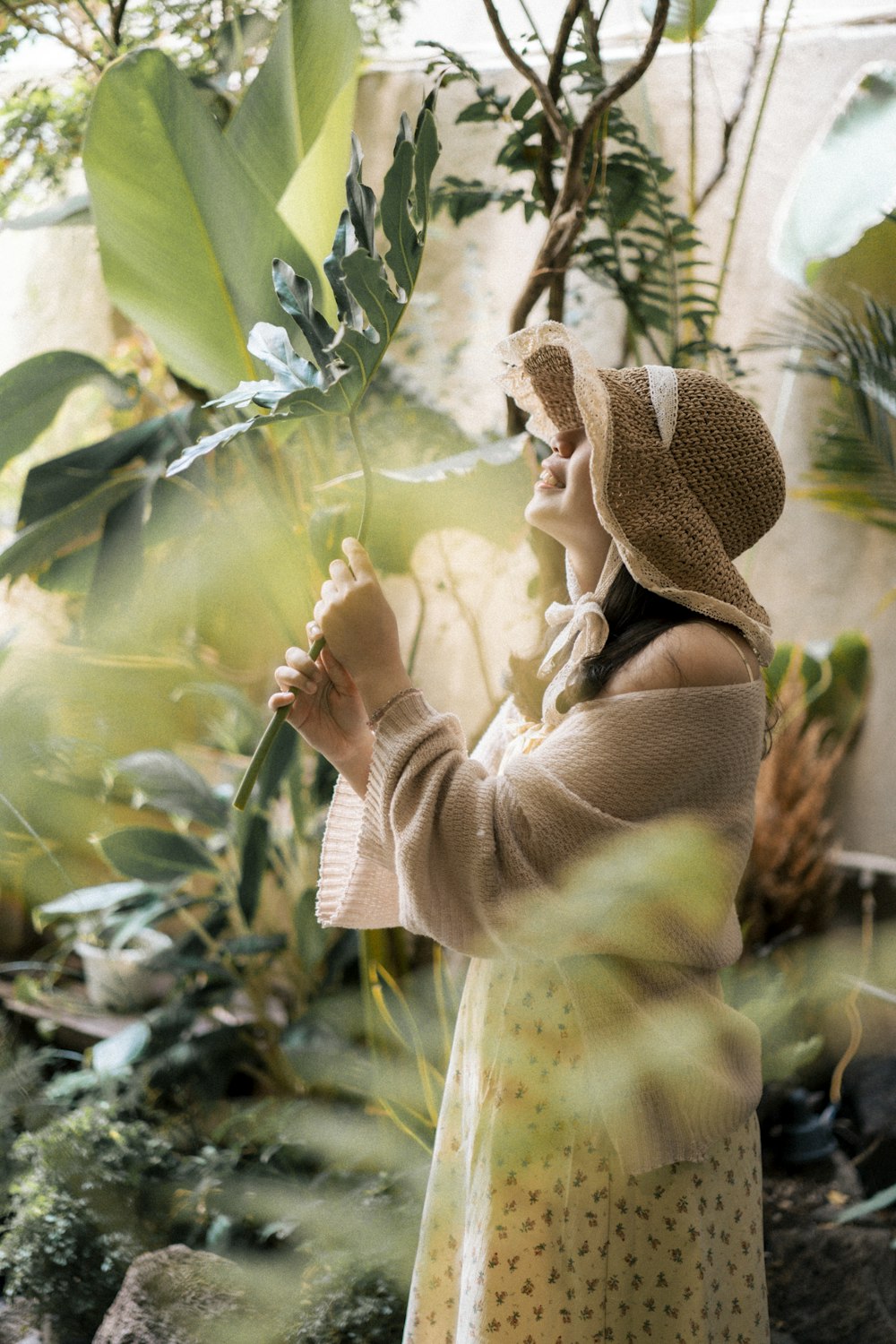 a woman in a hat is holding a plant