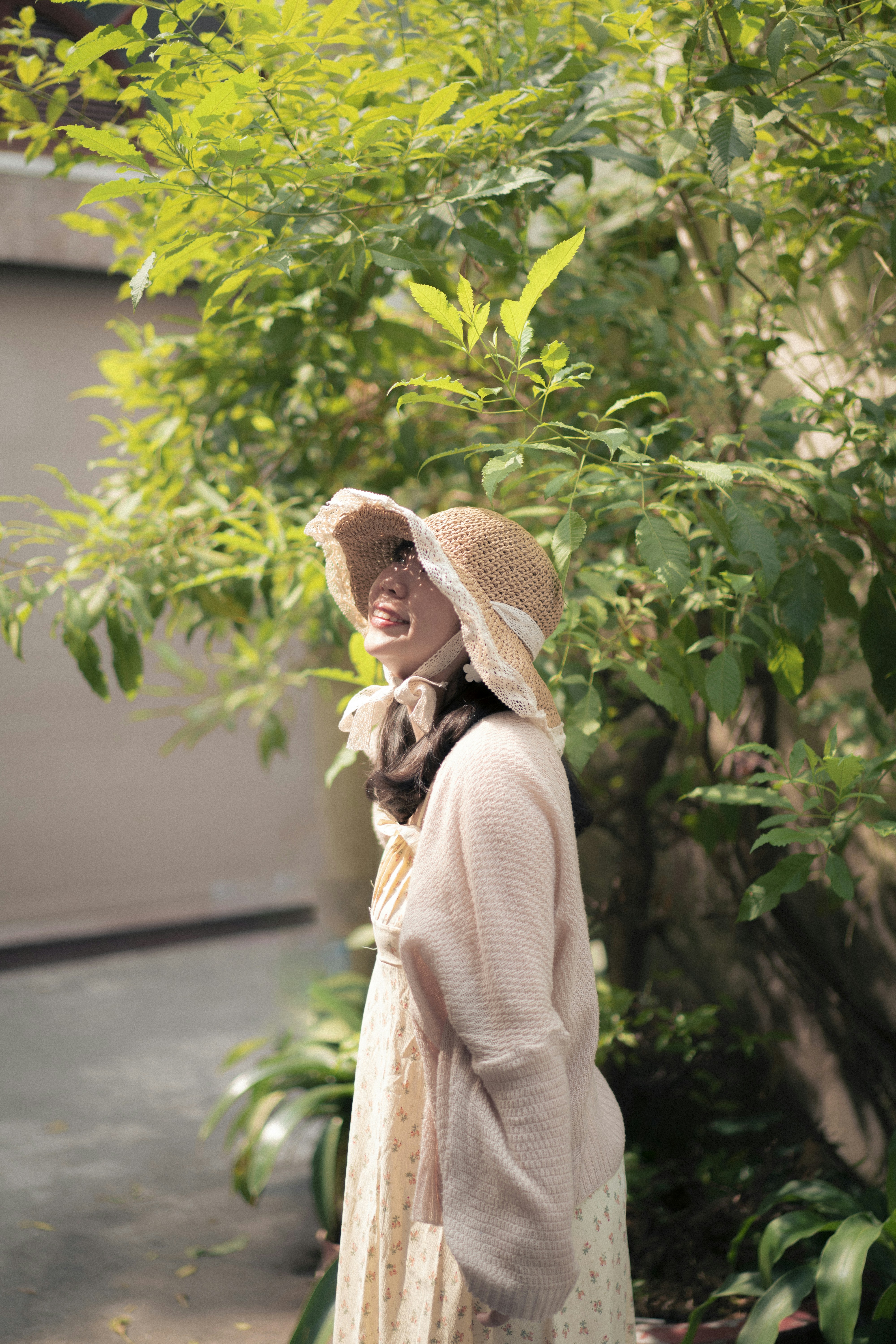 a woman in a dress and hat walking down a street