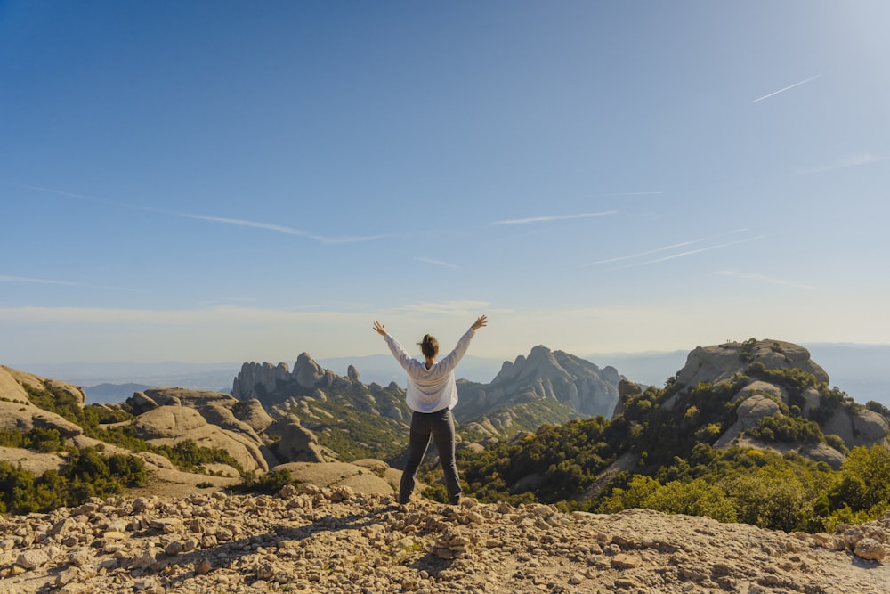 a person standing on top of a mountain with their arms in the air