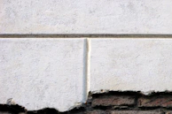 Laser cleaning in progress on a weathered concrete wall revealing fresh stone beneath.