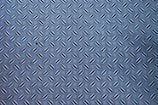 A metal surface with a diamond plate pattern, showing a series of raised, elongated shapes uniformly distributed across the surface.