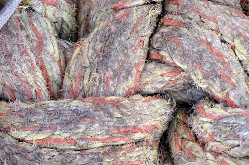 Thick, rugged ropes intertwine with visible fraying and wear, featuring natural fibers in earthy tones with red accents.