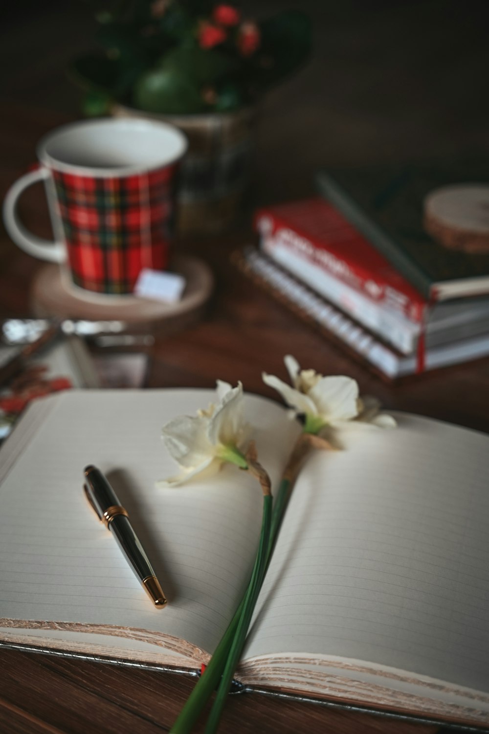 a notebook with a pen and flowers on a table