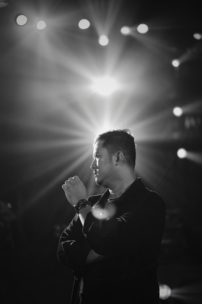 A black and white portrait of Juan Vargas on stage, spotlight highlighting his focused expression.