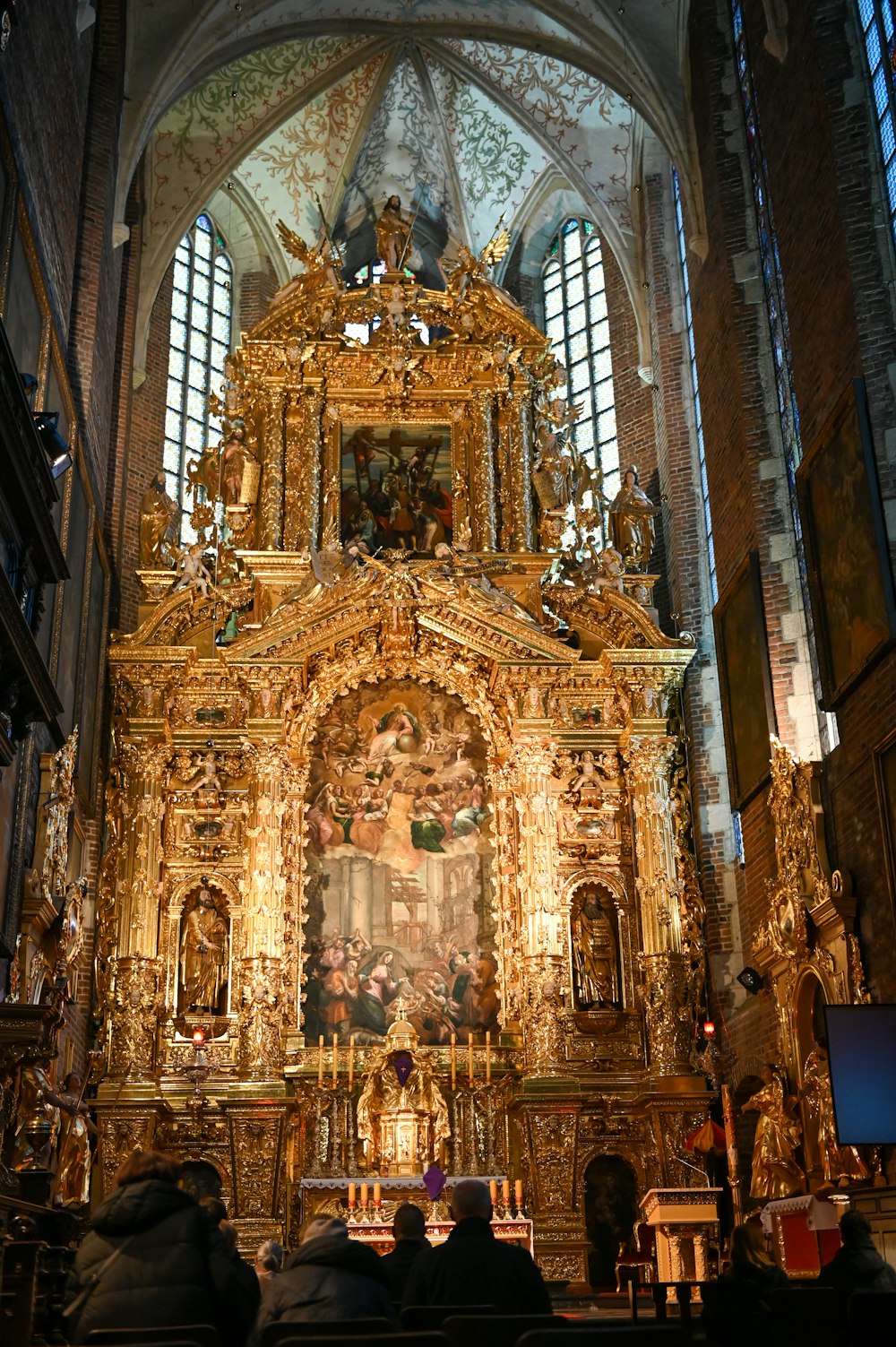 a church with a golden alter and a large painting on the wall