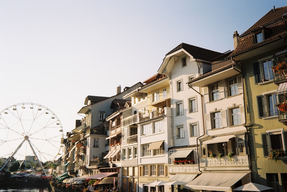 a large ferris wheel sitting next to a row of buildings