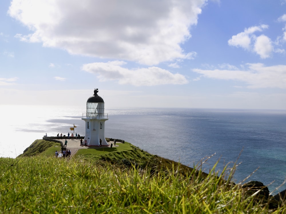 a lighthouse on a grassy hill overlooking the ocean