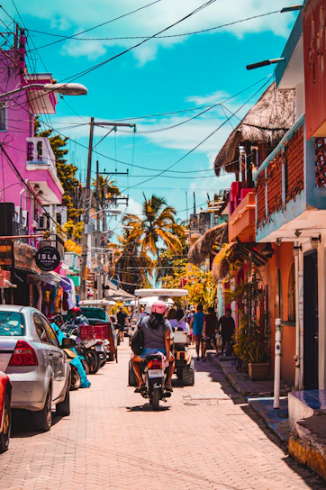A vibrant street scene in Tanza, Cavite with locals engaging in daily activities under a bright sky.