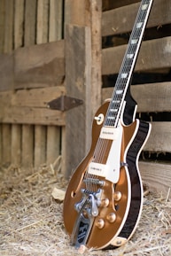 A vintage electric guitar resting on a workbench surrounded by tools and guitar parts.
